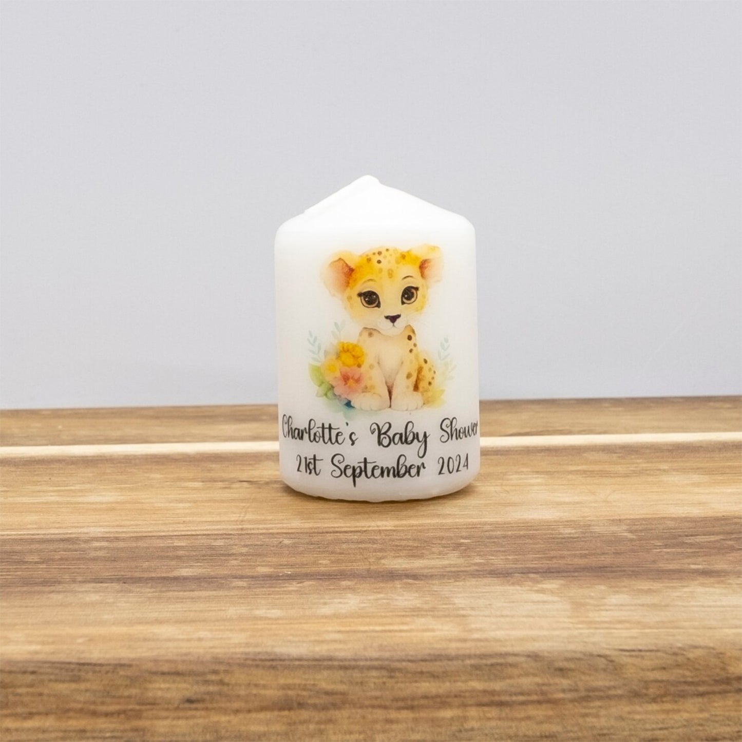 Candle with a lion cub design on a wooden surface