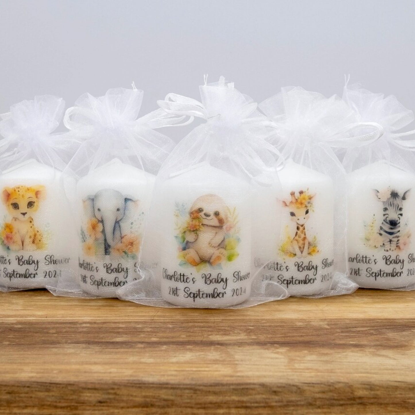 Set of baby shower favors with animal illustrations in clear bags on a wooden surface.