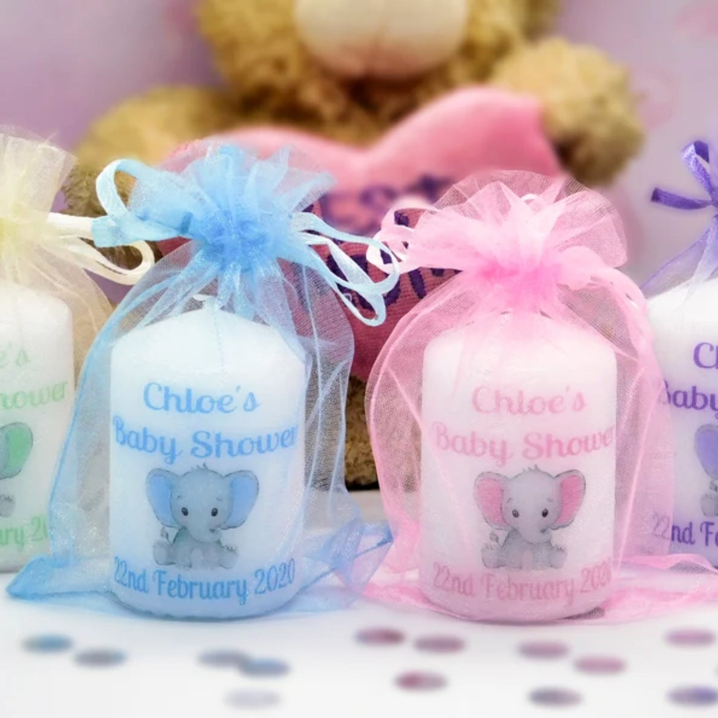 A set of four customized baby shower candle favours with elephant design, each in a different color, tied with organza ribbons.