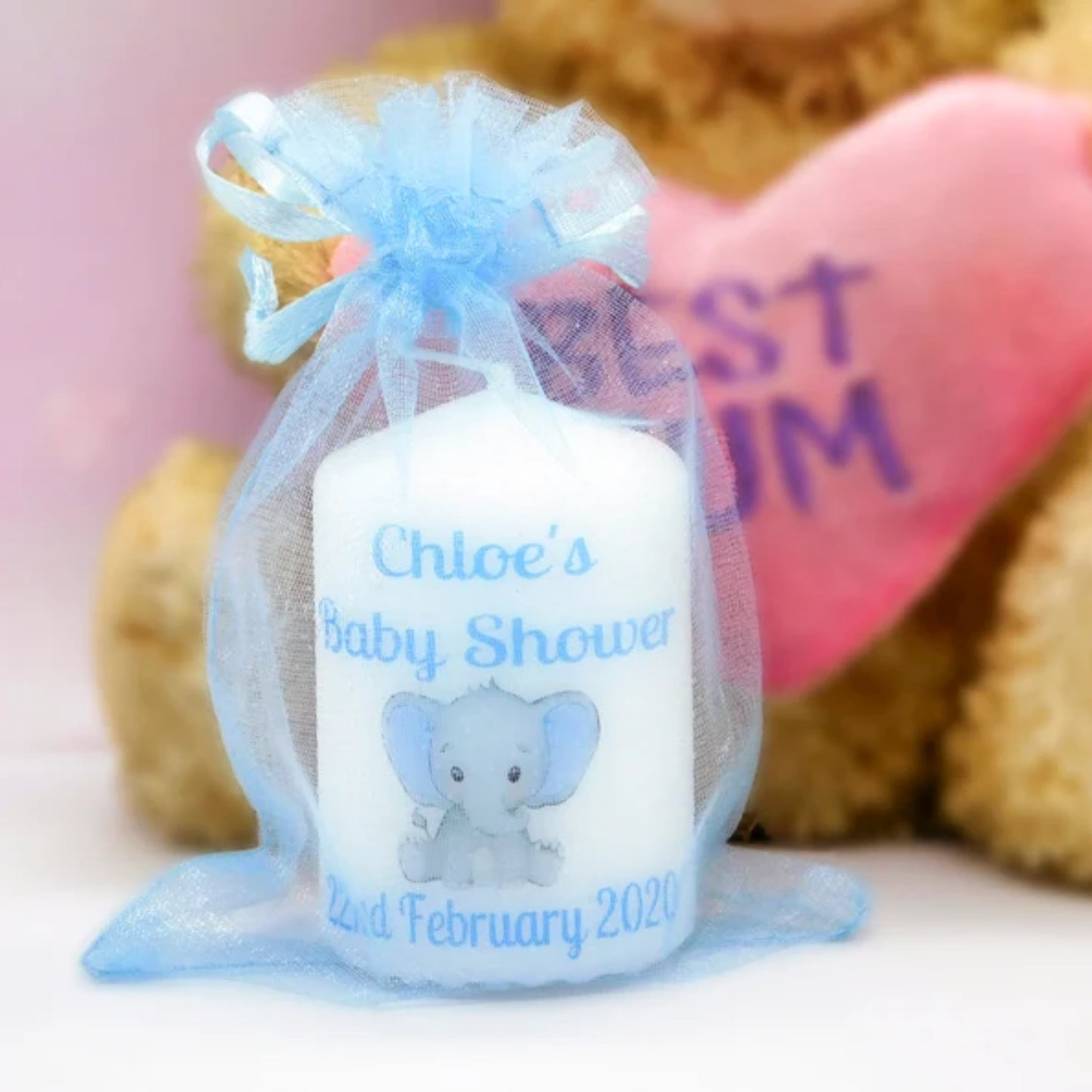 A set of four customized baby shower candle favours with elephant design, each in a different color, tied with organza ribbons.