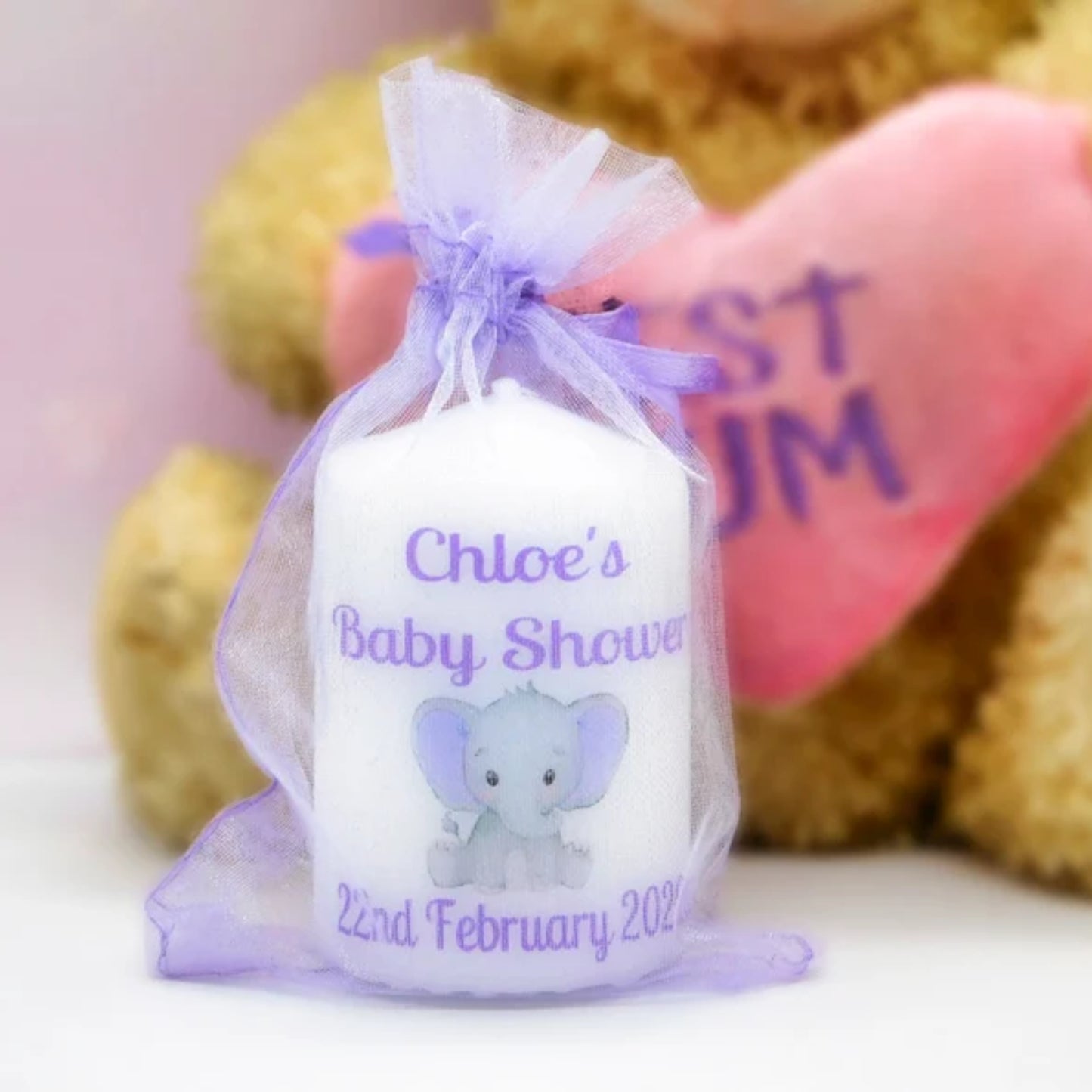 A set of four customized baby shower candle favours with elephant design, each in a different color, tied with organza ribbons.
