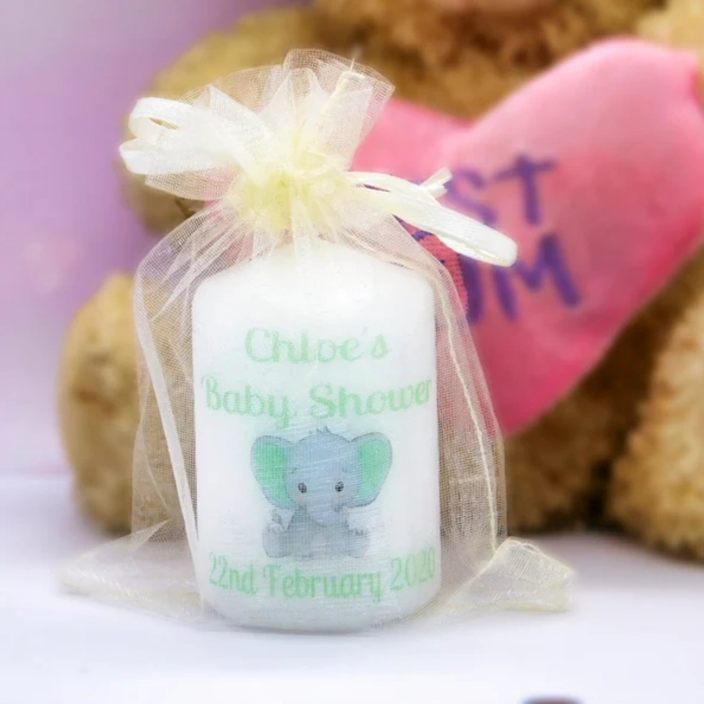 A set of four customized baby shower candle favours with elephant design, each in a different color, tied with organza ribbons.