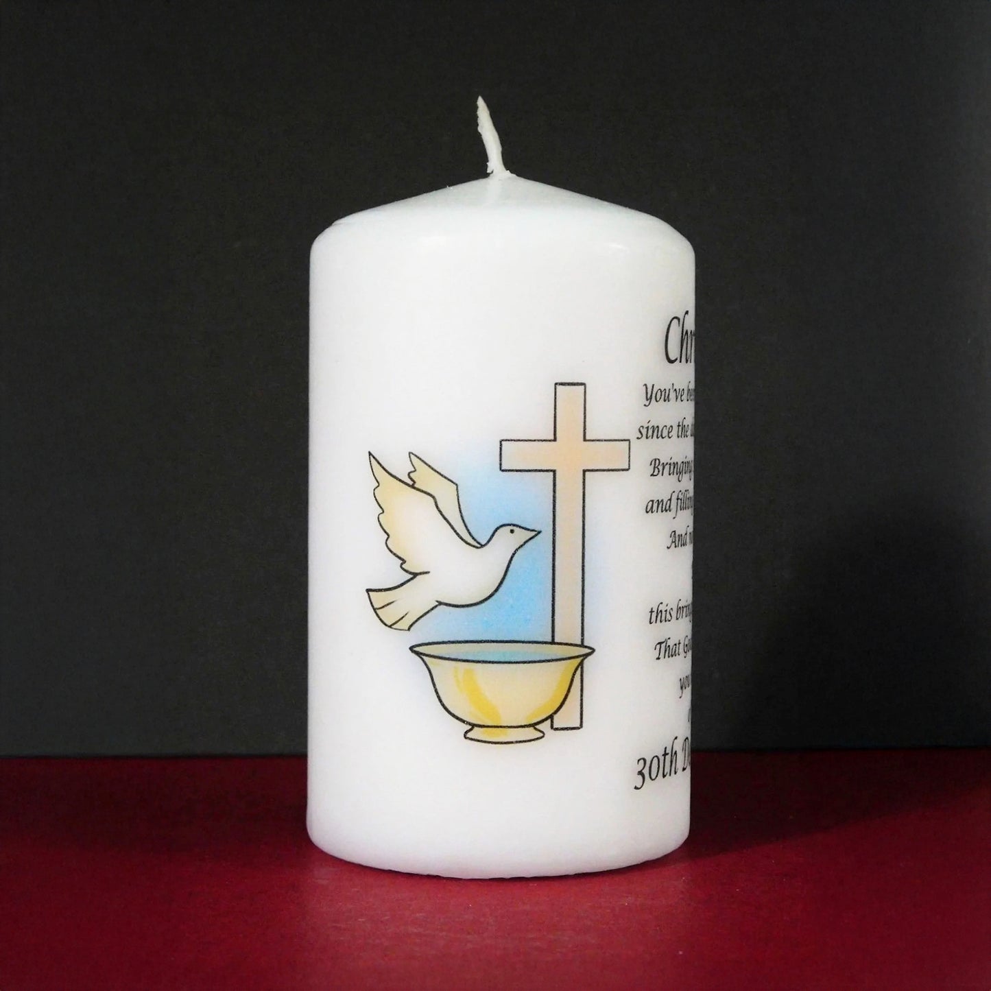 White candle with religious symbols and text on a dark background