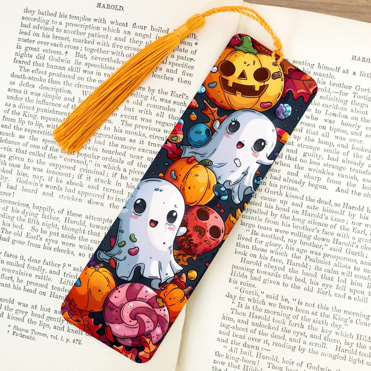 Colorful Halloween-themed bookmark with ghosts, pumpkins, and candy on a book page.