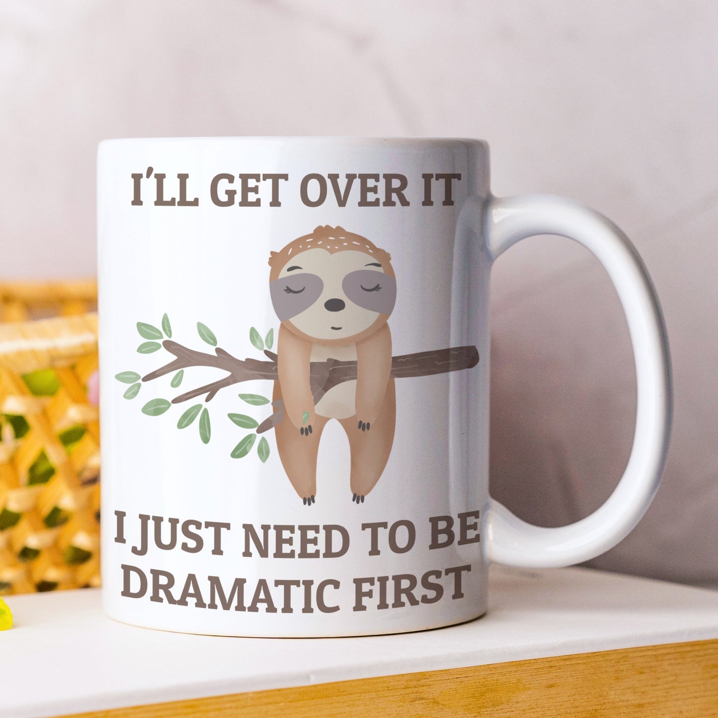 Mug with sloth illustration and humorous text on a white surface