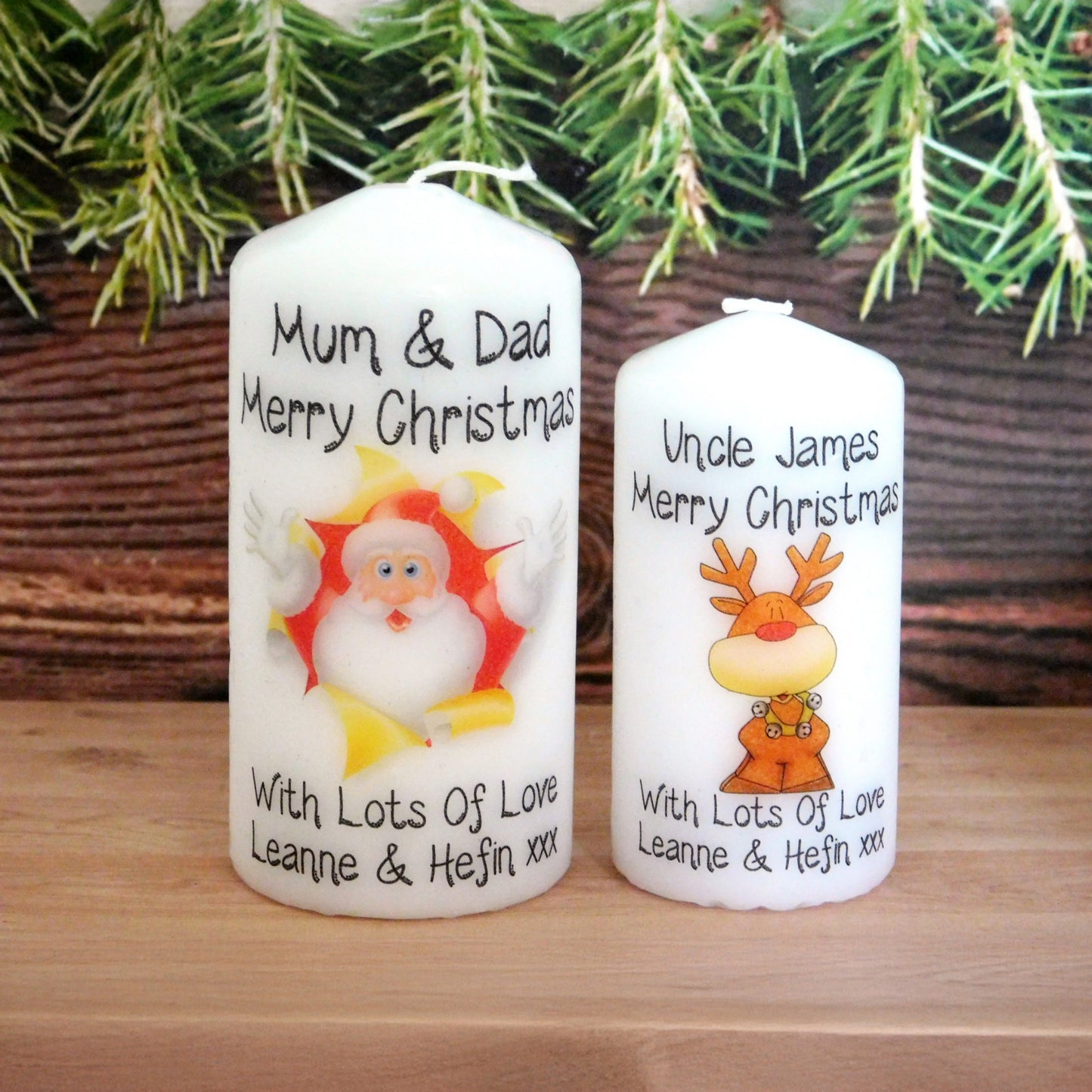 Two Christmas-themed candles with personalized messages in front of a Christmas tree.