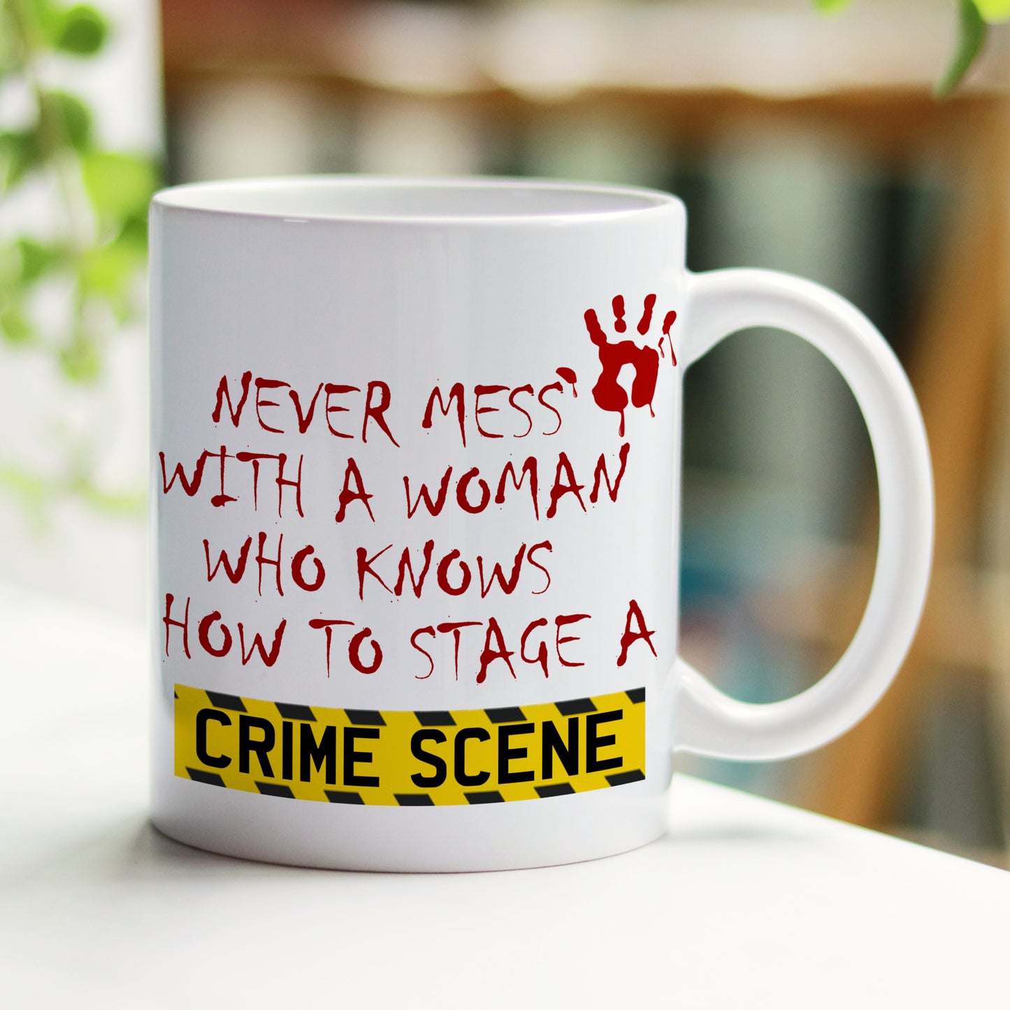 White mug with red and black text and a handprint on a blurred background