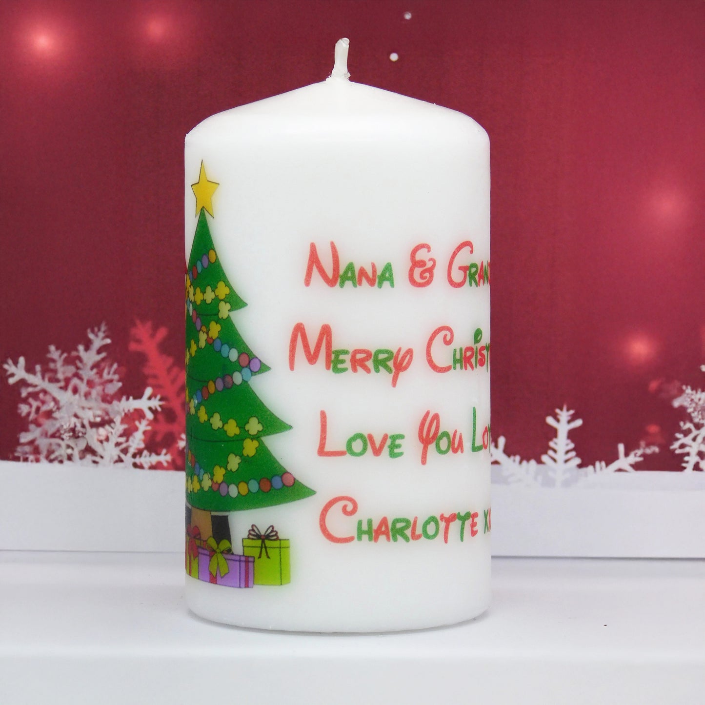 White Christmas-themed candle with decorative text and graphics on a red background