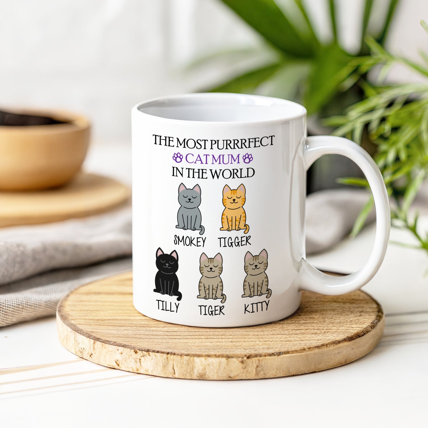 White mug with cat illustrations and text on a wooden coaster