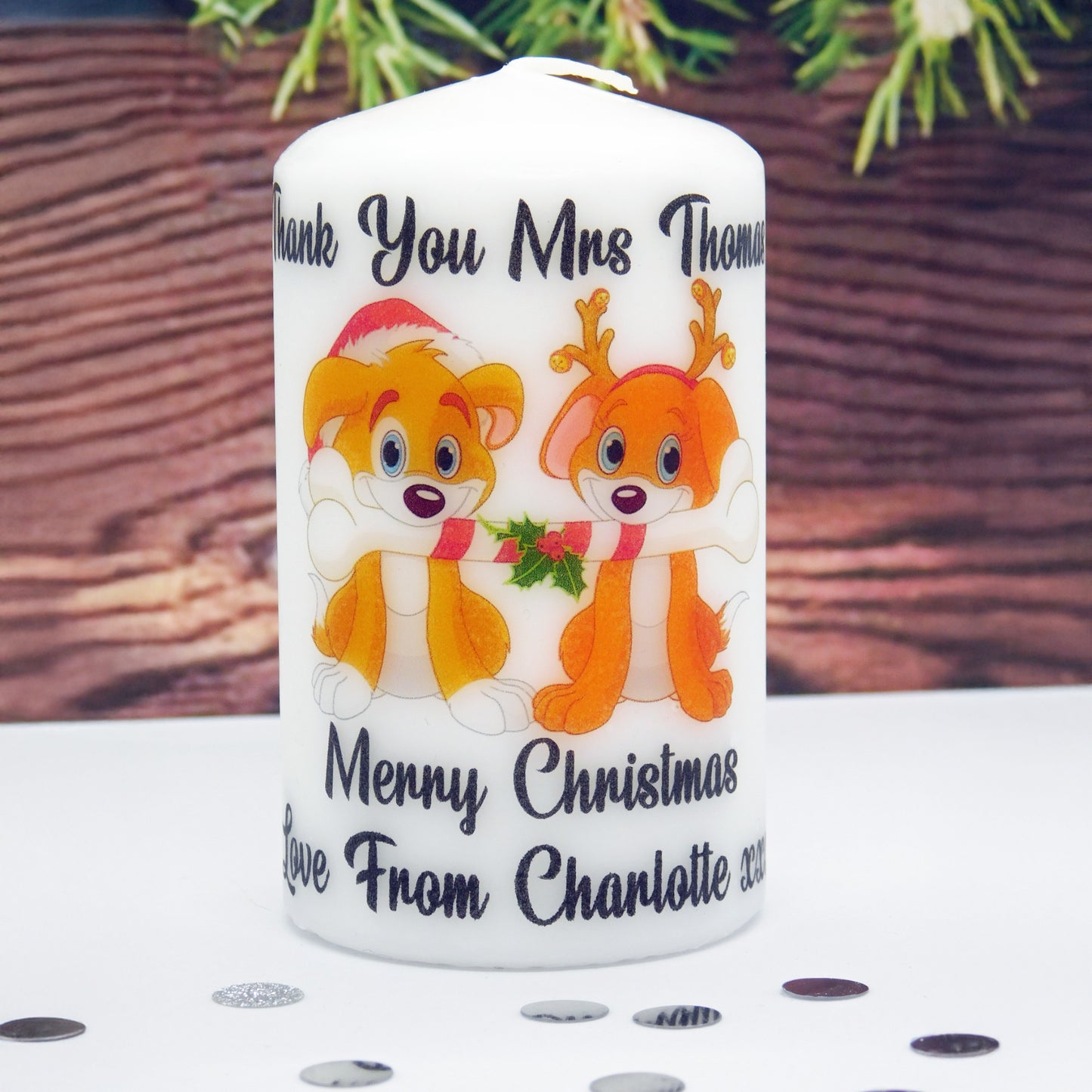 White candle with cartoon characters and Christmas text on a wooden surface