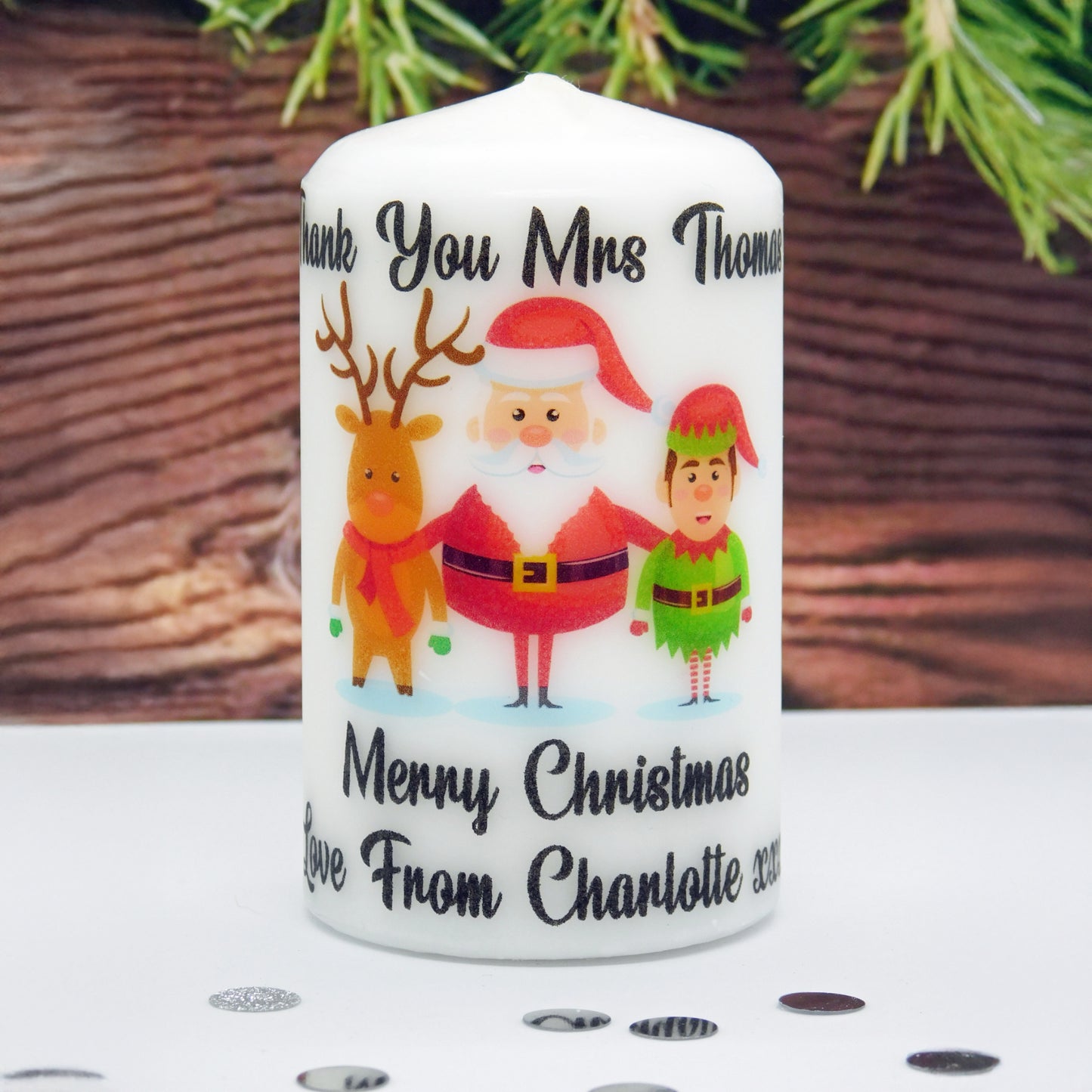 Personalized Christmas candle with Santa, reindeer, and elf design on a wooden surface.