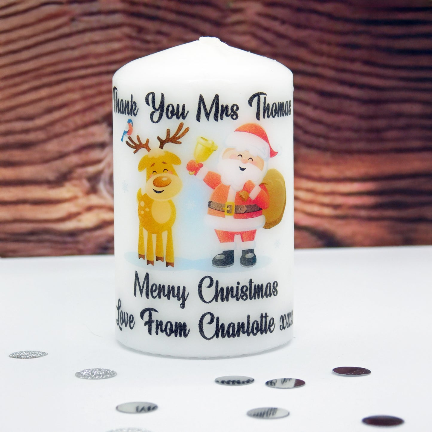 Personalized Christmas candle with Santa and reindeer design on a wooden surface.