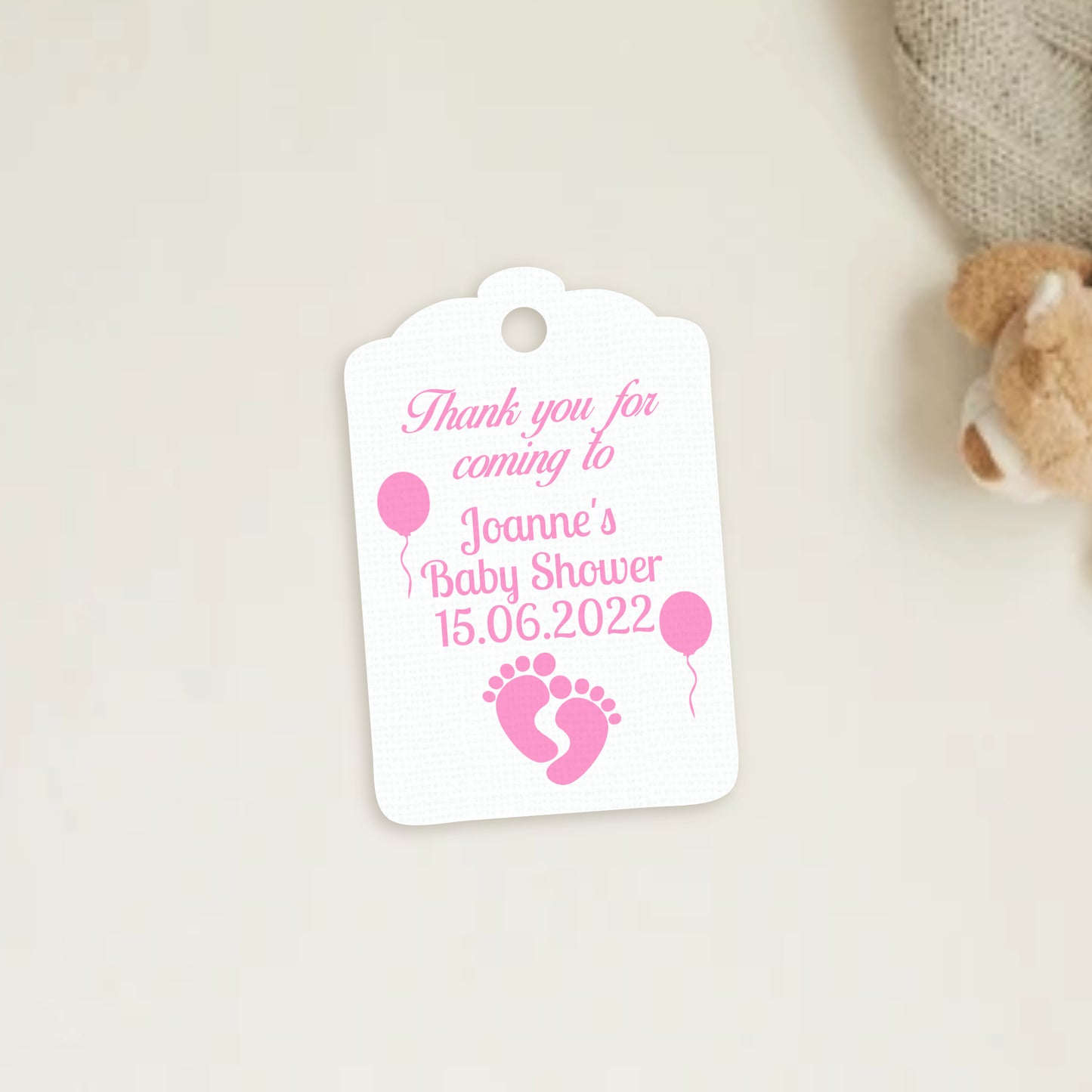 Three white square gift tags with rounded corners, each featuring a baby footprint design in blue, pink, or grey, along with personalized text for a baby shower. The tags are presented on a neutral background.