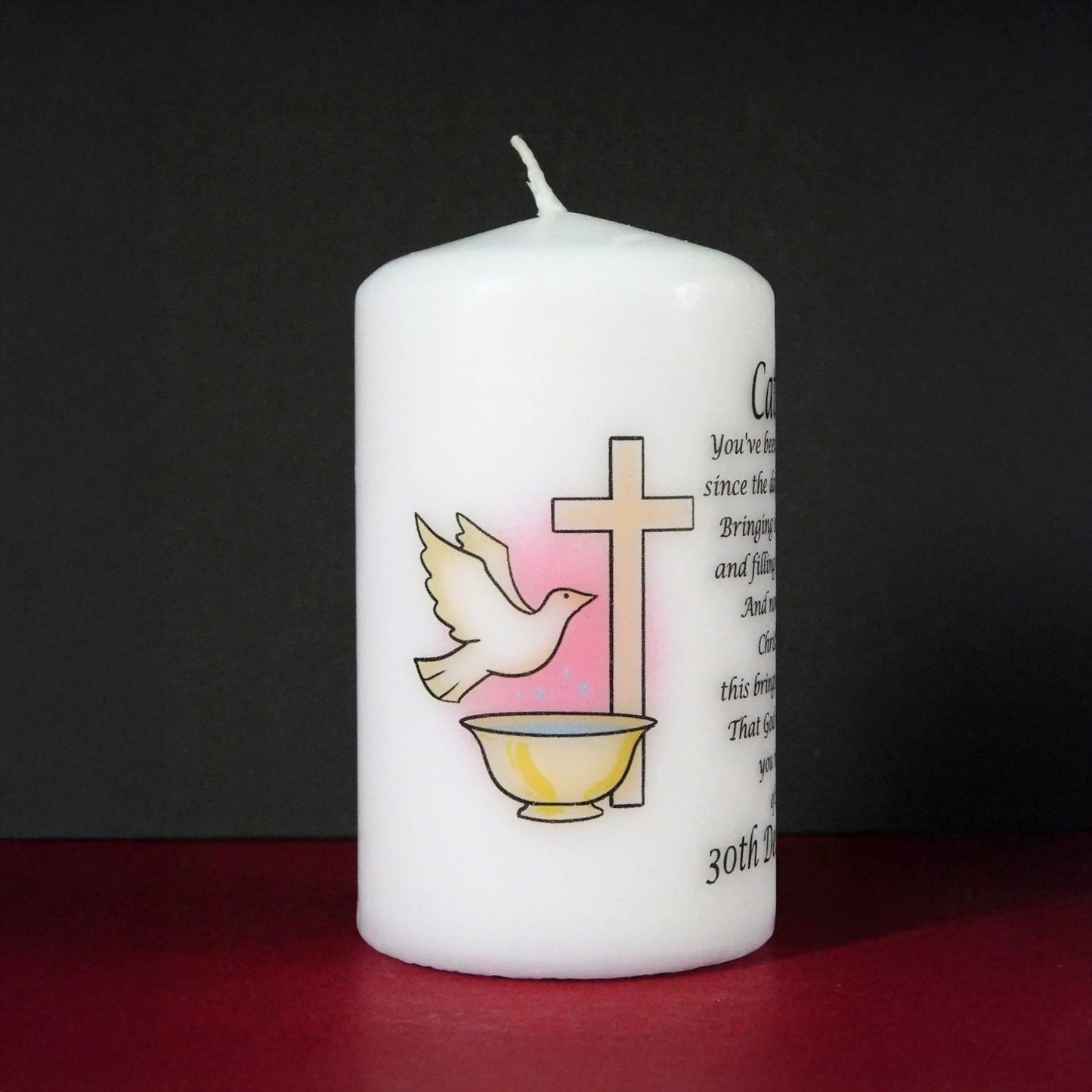 White candle with religious symbols and text on a dark background