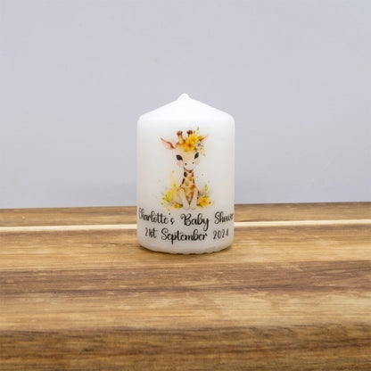 White candle with a baby shower design on a wooden surface