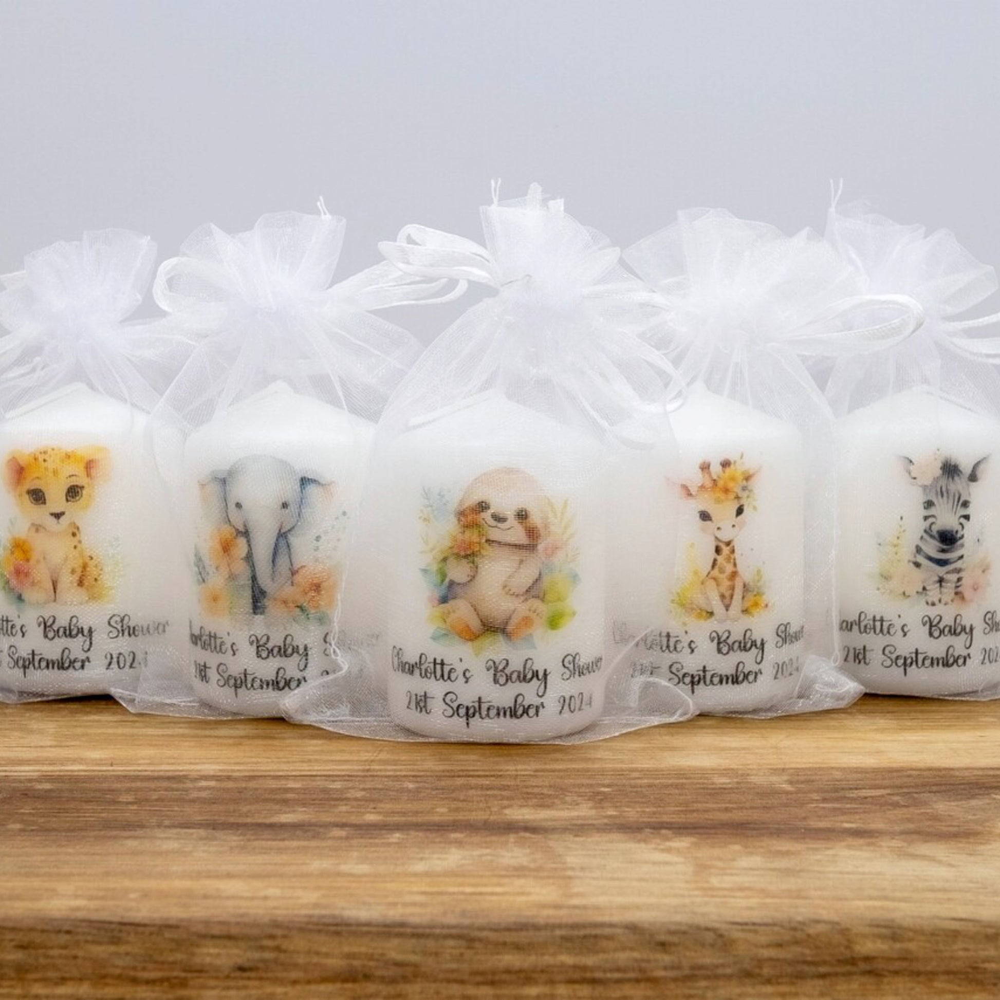 Set of baby shower favors with animal illustrations in clear bags on a wooden surface.