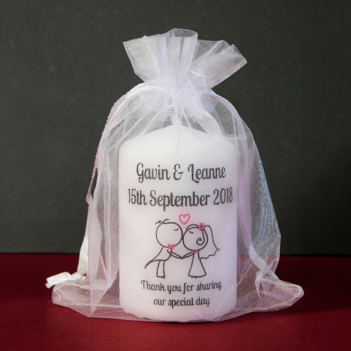 Personalized candle in a sheer white bag with text and graphics on a dark background