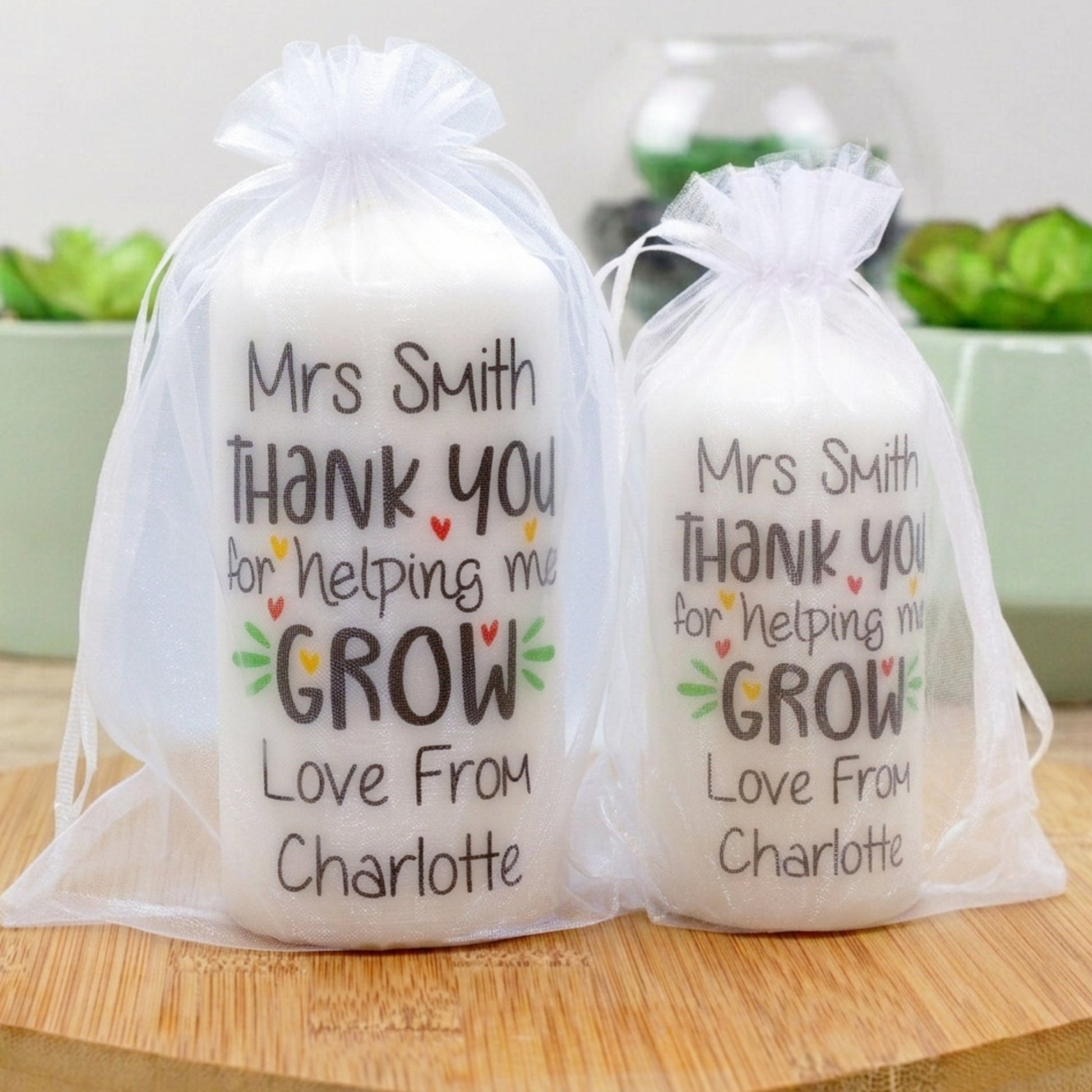 Two personalised candles with the phrase 'Thank You For Helping Me Grow', with a space for a custom name, presented in clear packaging.