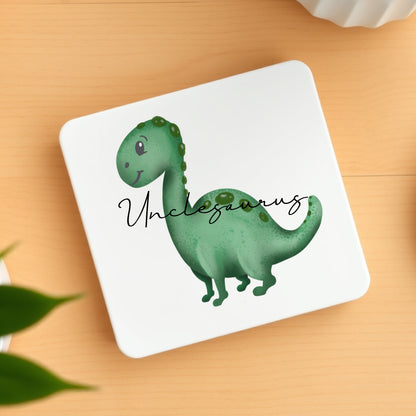 Coaster with a green dinosaur illustration and 'Unclesaurus' text on a wooden surface.