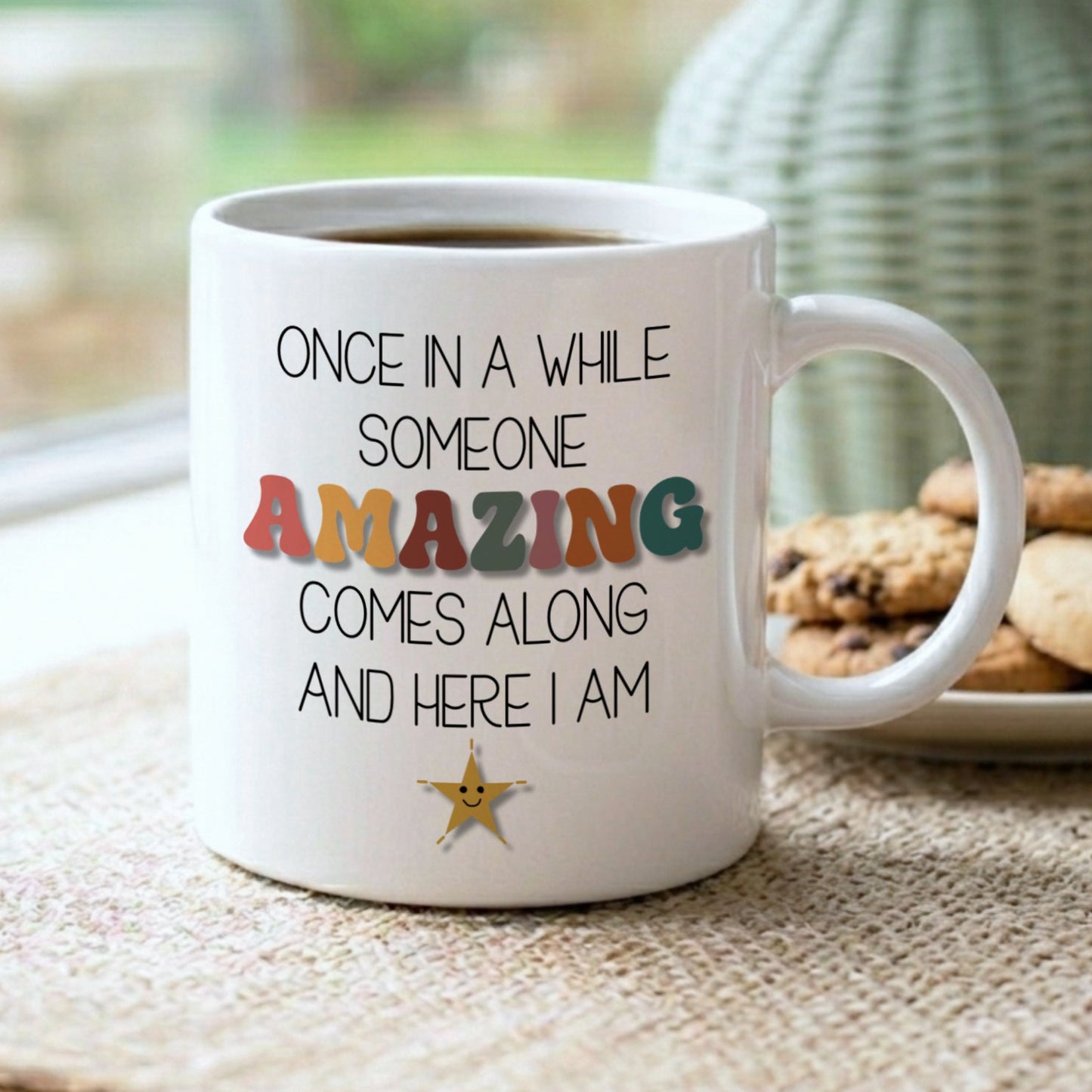 White mug with motivational quote on a table with cookies and a vase in the background