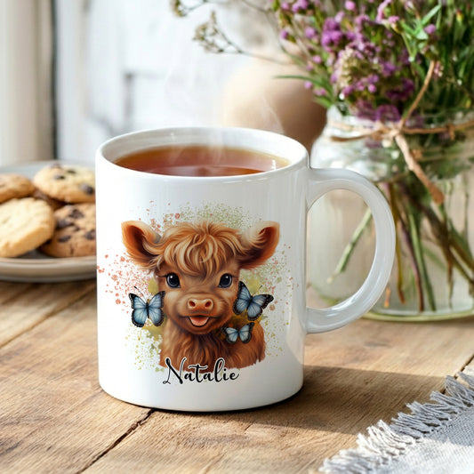 White mug with a cow design and the name 'Natalie', filled with tea, on a wooden table.