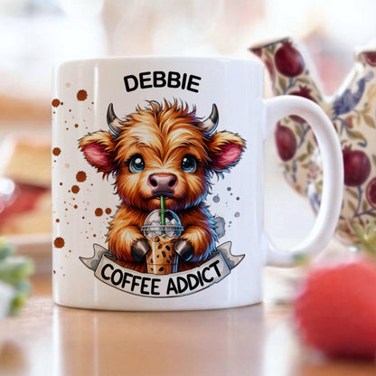 Mug with a cartoon cow design and text 'Debbie Coffee Addict' on a table with a teapot and fruit.