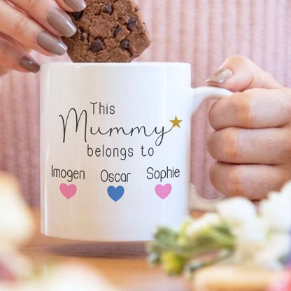 Person holding a mug labeled 'Sarah Bride to be' with a cookie, blurred background