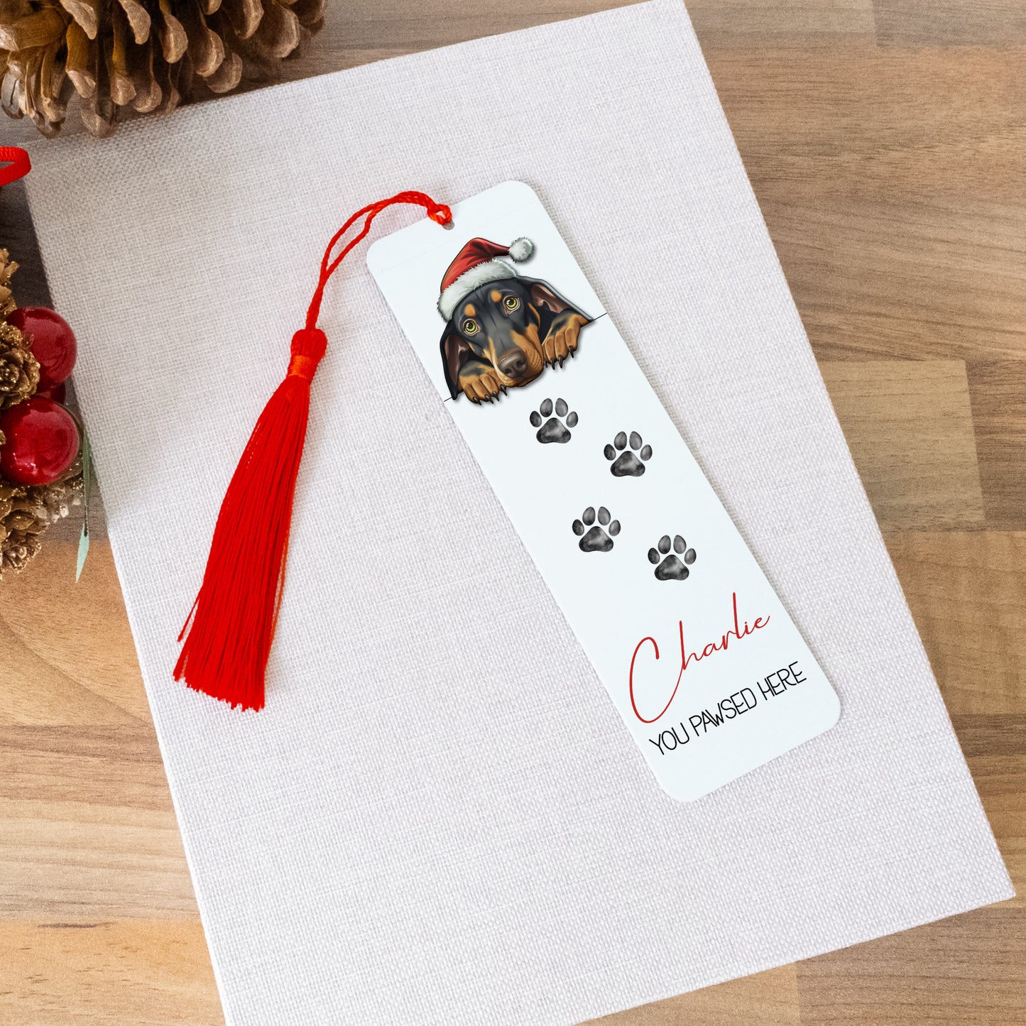 Bookmark with a dog illustration and tassel on a white card with Christmas decorations.