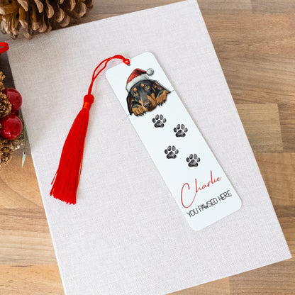 Bookmark with a dog illustration and tassel on a white card with Christmas decorations.