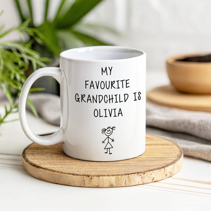 A white mug with my favourite grandchild is Olivia text on a wooden coaster with a blurred background