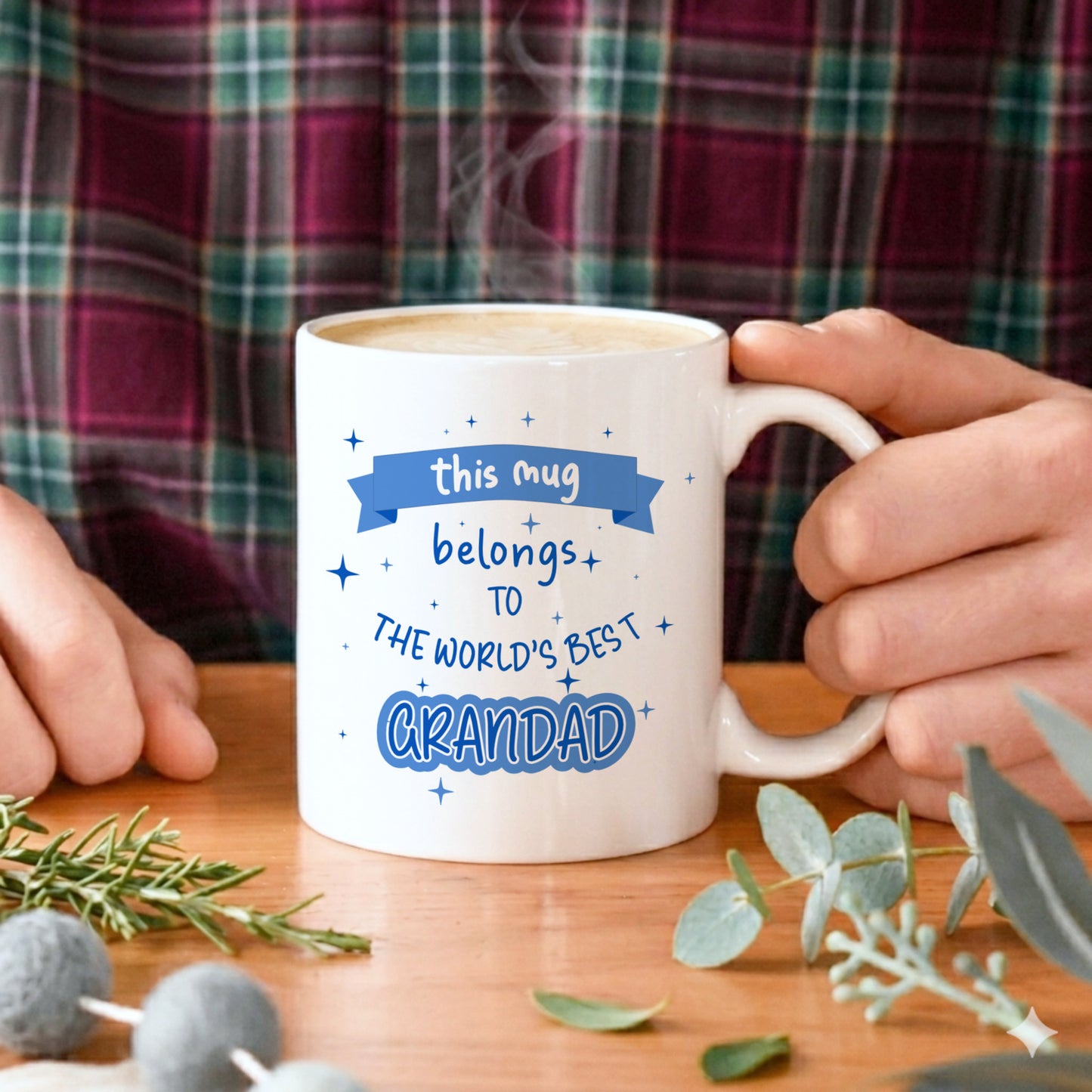 A man holding a white mug with "this mug belongs to the World's best Grandad" text in blue 