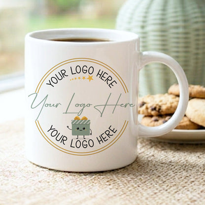 White mug with customizable logo area on a table with cookies and a vase in the background