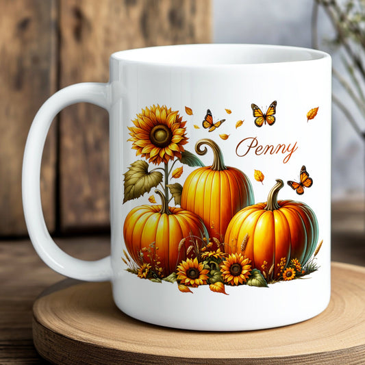 White mug with autumn-themed design featuring pumpkins and sunflowers on a wooden surface.