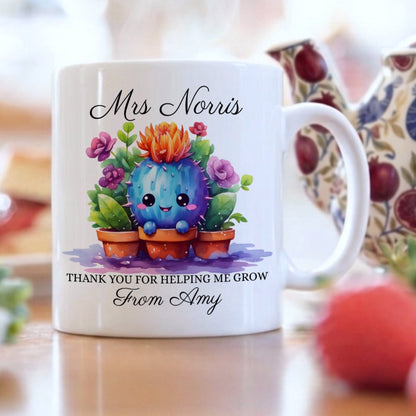 Personalised teacher appreciation mug with kawaii-style cactus in terracotta pots surrounded by purple and orange flowers, personalised with 'Mrs Norris' and 'Thank You For Helping Me Grow From Amy', displayed on a wooden table with a floral teapot and fresh strawberries