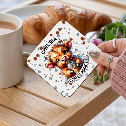 Card with a dog illustration and text 'Coffee Addict' held by a person over a cup of coffee and croissant.