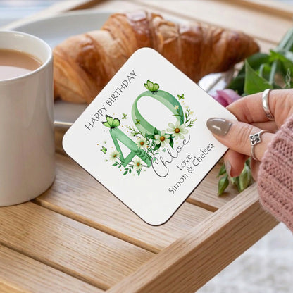 Coaster with floral design and text on a wooden table with coffee and croissant