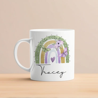 White mug with a colorful design featuring a rainbow, flowers, and butterflies on a beige background.
