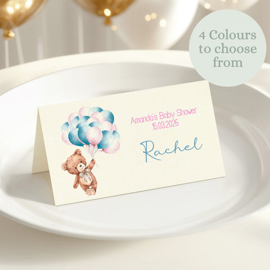Place card with teddy bear and balloons on a white plate with gold balloons in the background
