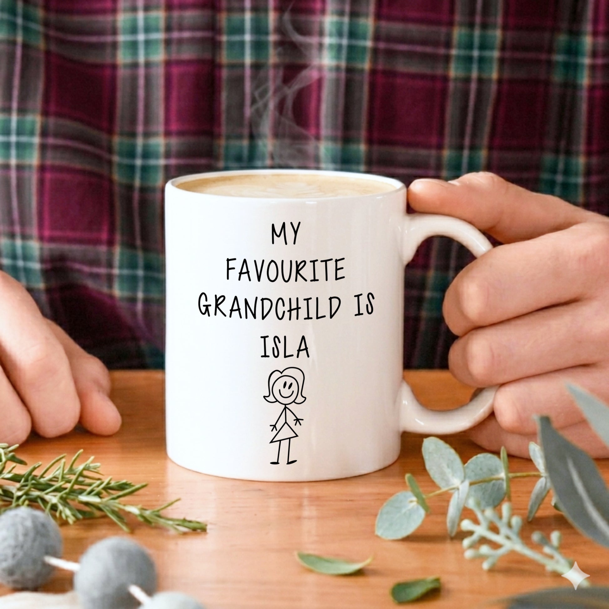 Aman holding a white mug with the text My favourite grandchild is Isla written on it