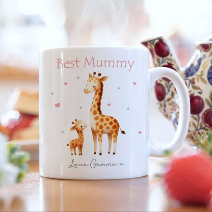 White mug with giraffe illustration and text 'Best Mummy Love Gemma' on a blurred background