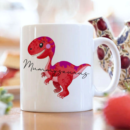 White mug with a red dinosaur design and 'Mummiosaurus' text on a blurred background