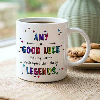 White mug with colourful text on a table with cookies and a vase in the background