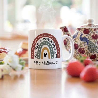 White mug with rainbow design and 'Mrs Matthews' text on a kitchen counter.