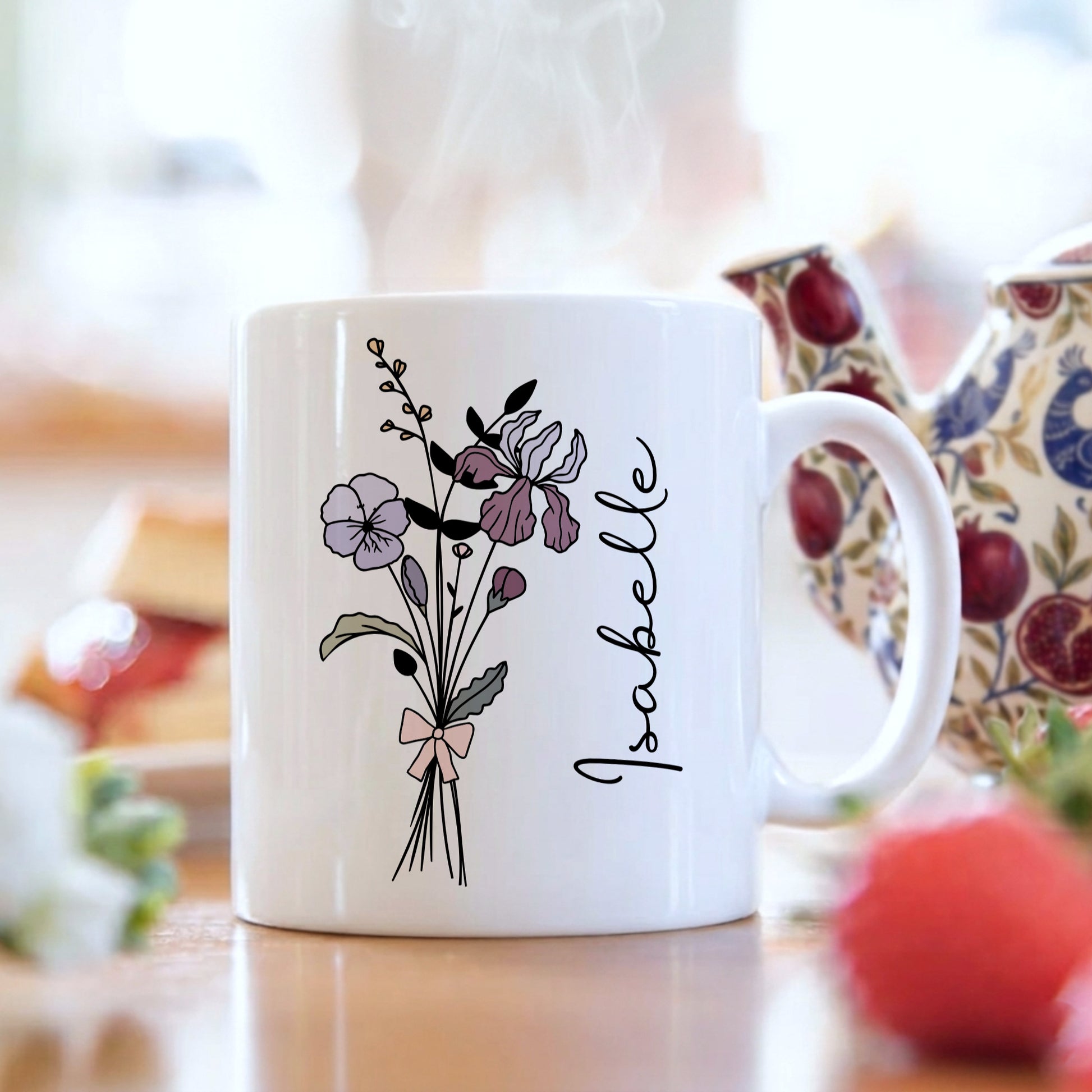 White mug with floral design and 'Isabelle' text on a blurred background