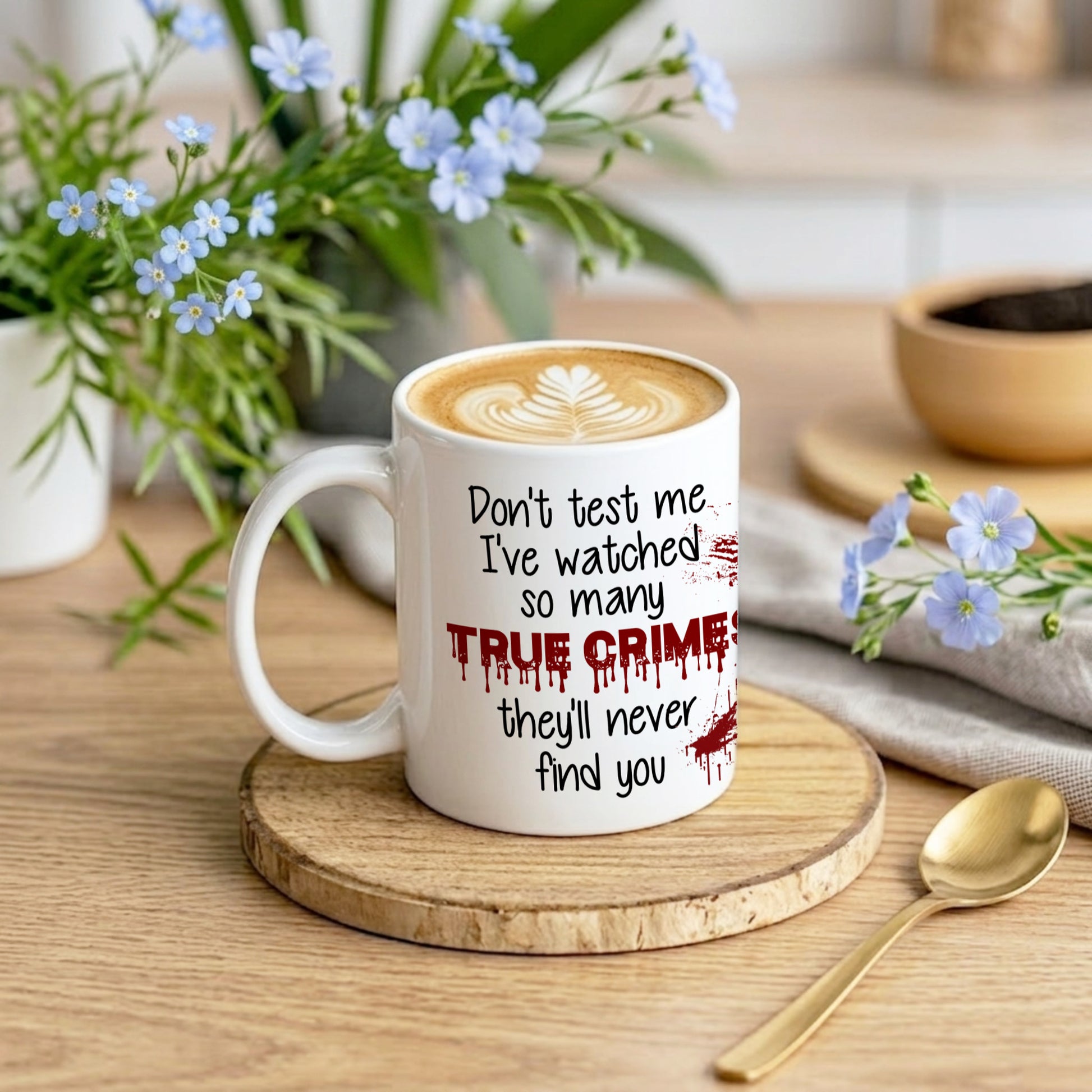 White mug with text on a wooden coaster with flowers and a bowl in the background