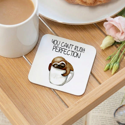 Coaster with sloth illustration and 'You can't rush perfection' text on a wooden table with coffee and flowers.