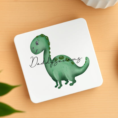 Coaster with a green dinosaur illustration and 'Daddyaurus' text on a wooden surface.
