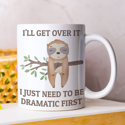 Mug with sloth illustration and humorous text on a white surface