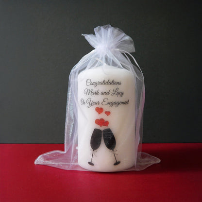 Engagement-themed candle with a祝福message in a clear bag on a red surface.