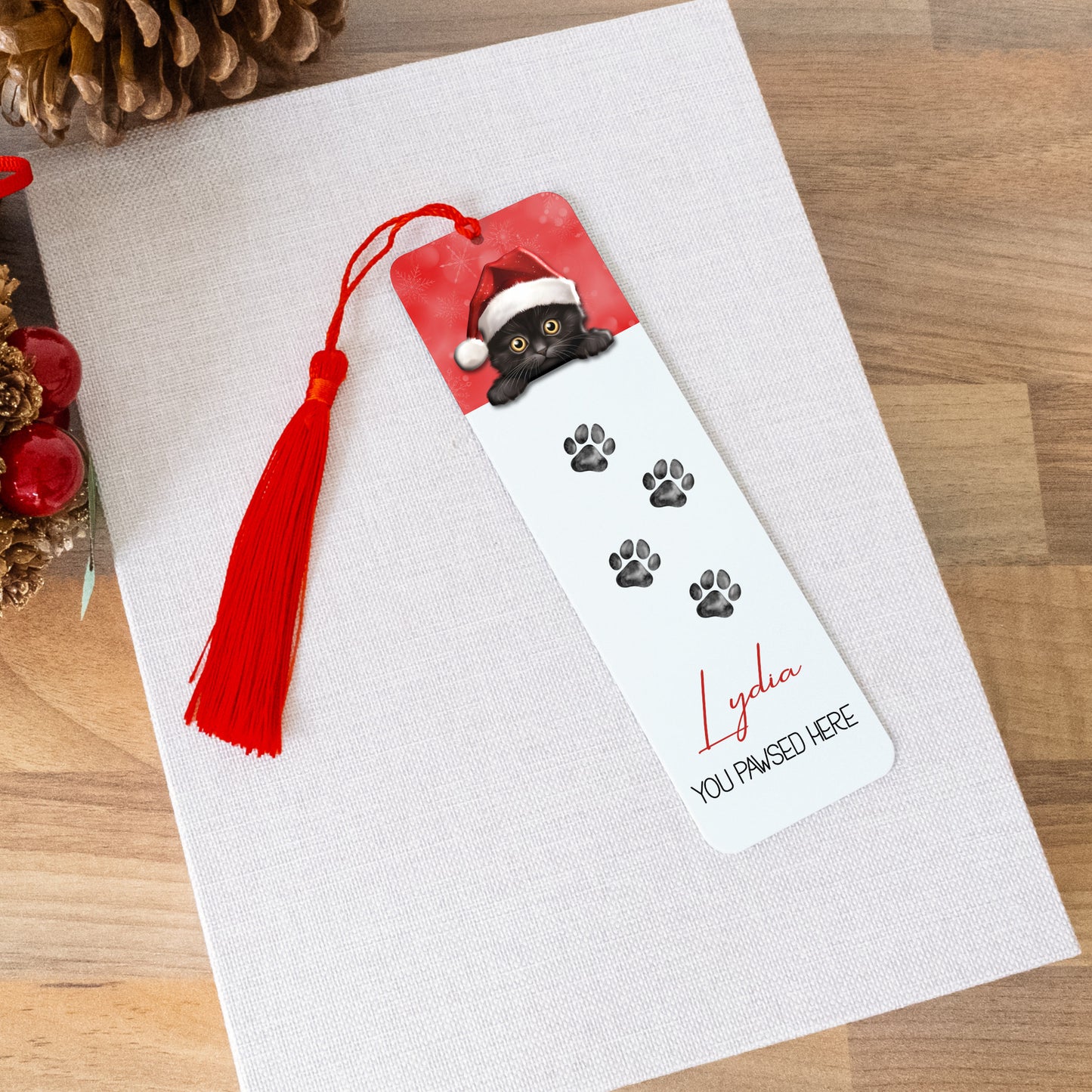 Personalized bookmark with a cat design and tassel on a white surface.